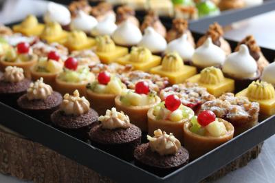 Miniature Traiteur Magny-les-Hameaux (Yvelines) - Lars Traiteur #27 Gâteau de fête décoré de bougies scintillantes, entouré de desserts et de convives en arrière-plan flou.