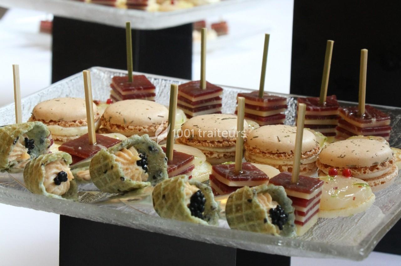 Assortiment de bouchées apéritives comprenant macarons salés, gelées superposées et cornets garnis de mousse et caviar.