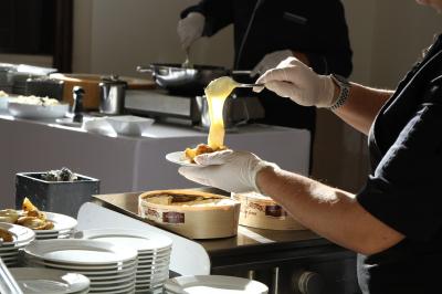 Miniature Traiteur Magny-les-Hameaux (Yvelines) - Lars Traiteur #32 Gâteau de fête décoré de bougies scintillantes, entouré de desserts et de convives en arrière-plan flou.