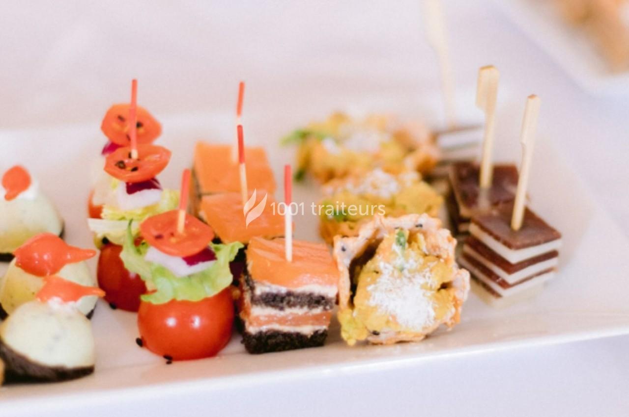 Assortiment de bouchées apéritives colorées sur un plateau, incluant légumes, saumon, fromage et desserts.