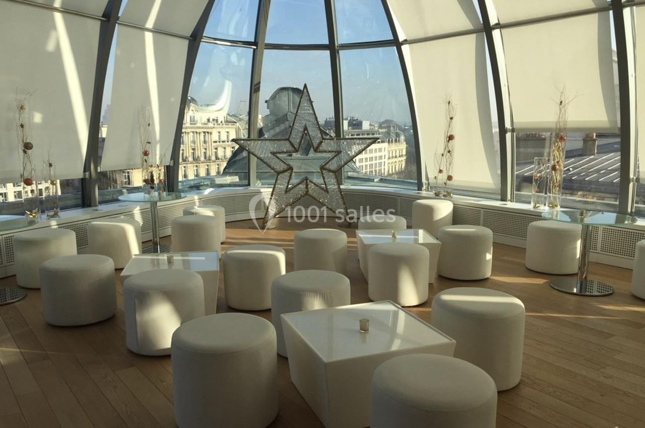 Salle lumineuse avec de grandes baies vitrées, mobilier blanc moderne et une étoile décorative au centre.