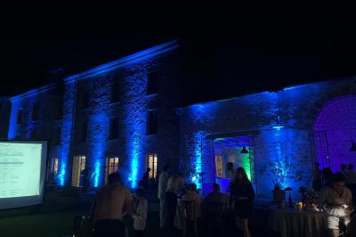 Tente blanche avec parois transparentes installée en extérieur sur un sol gravillonné, entourée d'arbres.