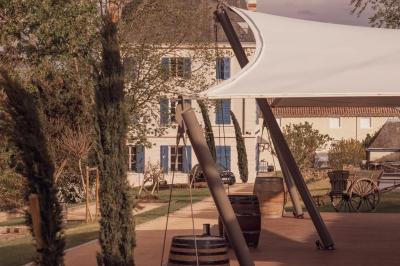 Miniature Justine Compagnon Wedding #8 Façade d'une maison ancienne avec volets bleus, entourée de végétation et éclairée par des guirlandes lumineuses.