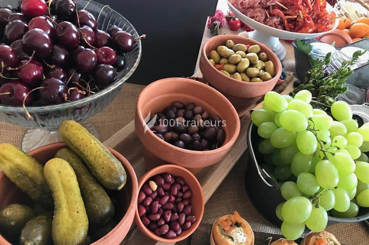 Assortiment de fruits, légumes, olives et amuse-bouches disposés sur une table pour un buffet.