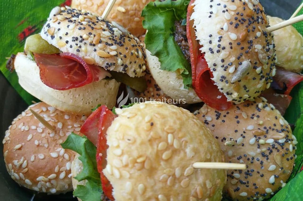 Mini-burgers garnis de salade, charcuterie et légumes, présentés sur un plateau avec des piques en bois.