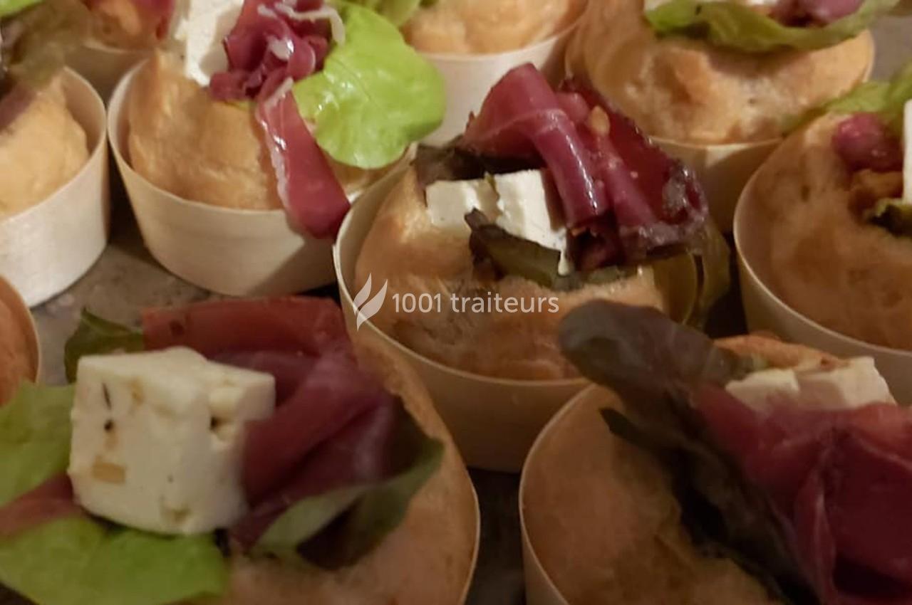 Petits choux garnis de salade, fromage frais et lamelles de viande séchée, présentés sur un plateau.