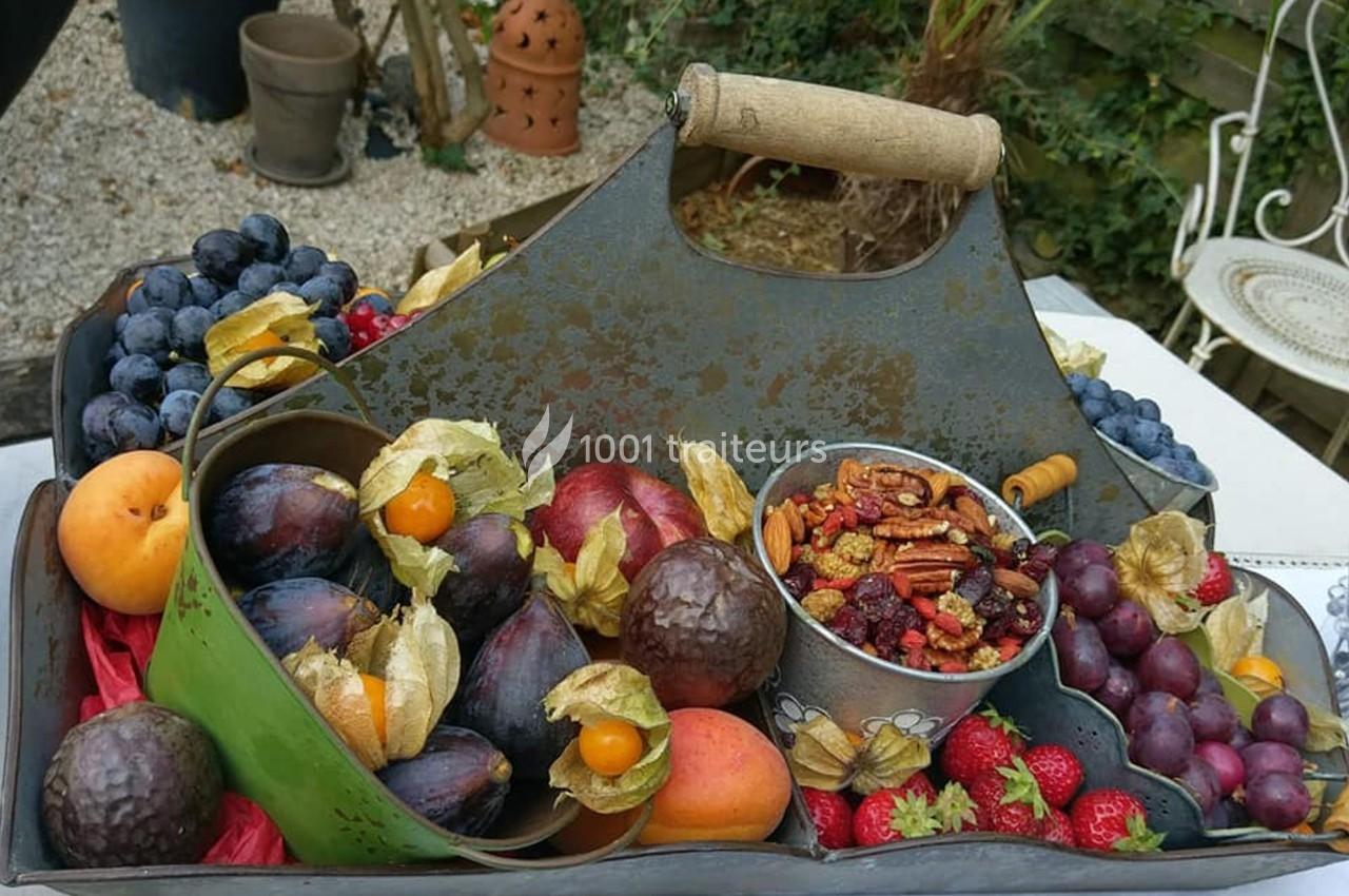 Plateau en métal contenant un assortiment de fruits frais, noix et baies, posé sur une table en extérieur.