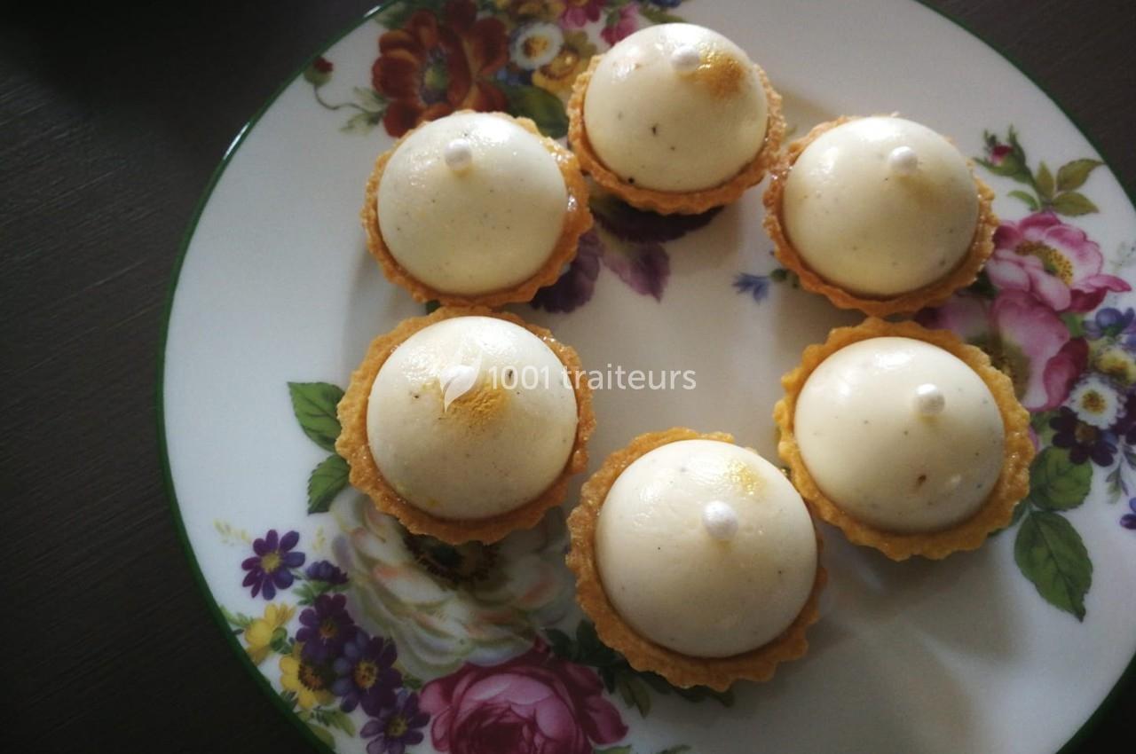Assortiment de tartelettes garnies de mousse blanche, présentées sur une assiette décorée de motifs floraux.
