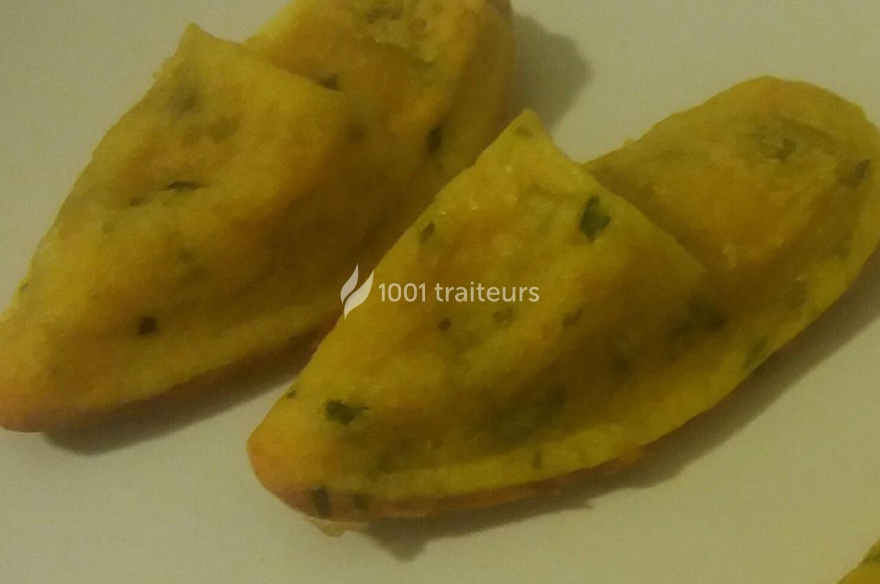 Deux beignets dorés en forme de demi-lune, garnis d'herbes, posés sur une assiette blanche.