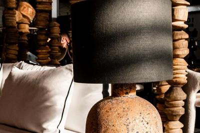 Sculpture de lion en pierre, table en bois sombre avec chandeliers noirs, vase bleu et décor rustique en arrière-plan.