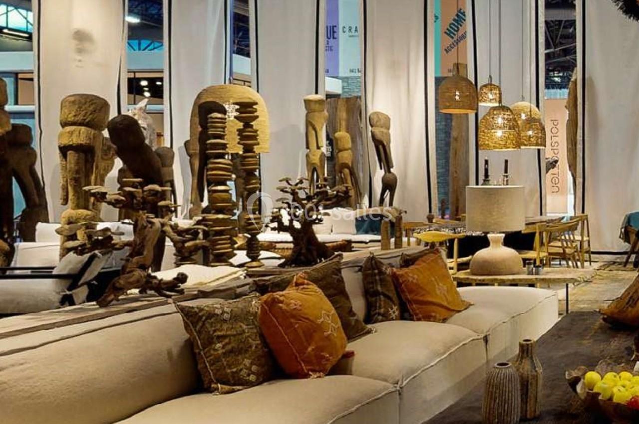 Canapé beige avec coussins colorés, décoré de sculptures en bois et éclairé par des suspensions en rotin.