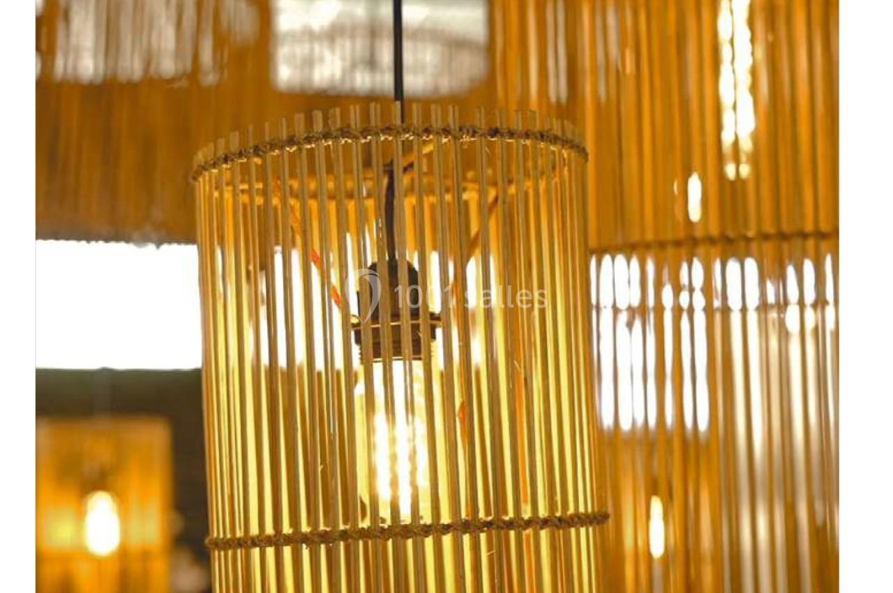 Suspension en bois composée de fines lamelles laissant passer la lumière d'une ampoule visible au centre.