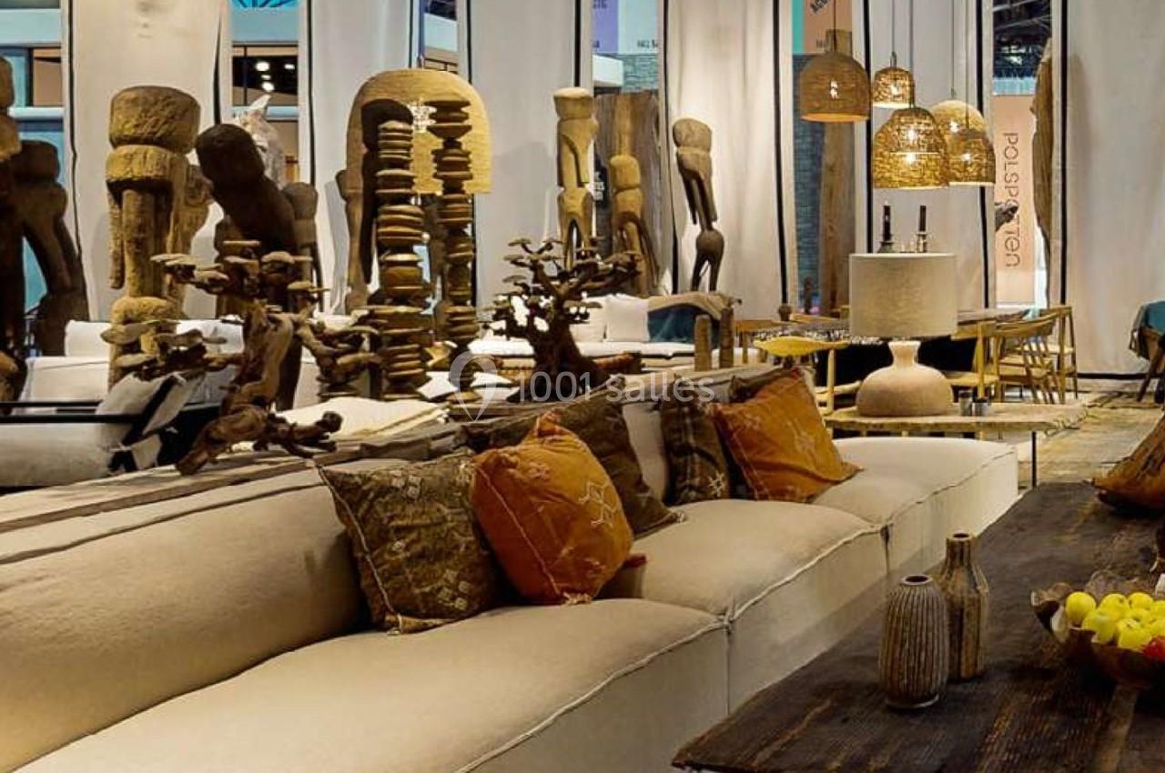 Canapés beiges avec coussins colorés, table basse en bois et sculptures décoratives dans un espace intérieur lumineux.