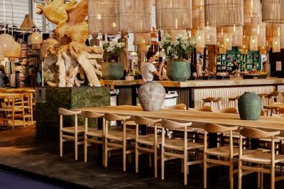 Tables en bois dressées avec des assiettes, des verres et des serviettes blanches dans une salle élégante.