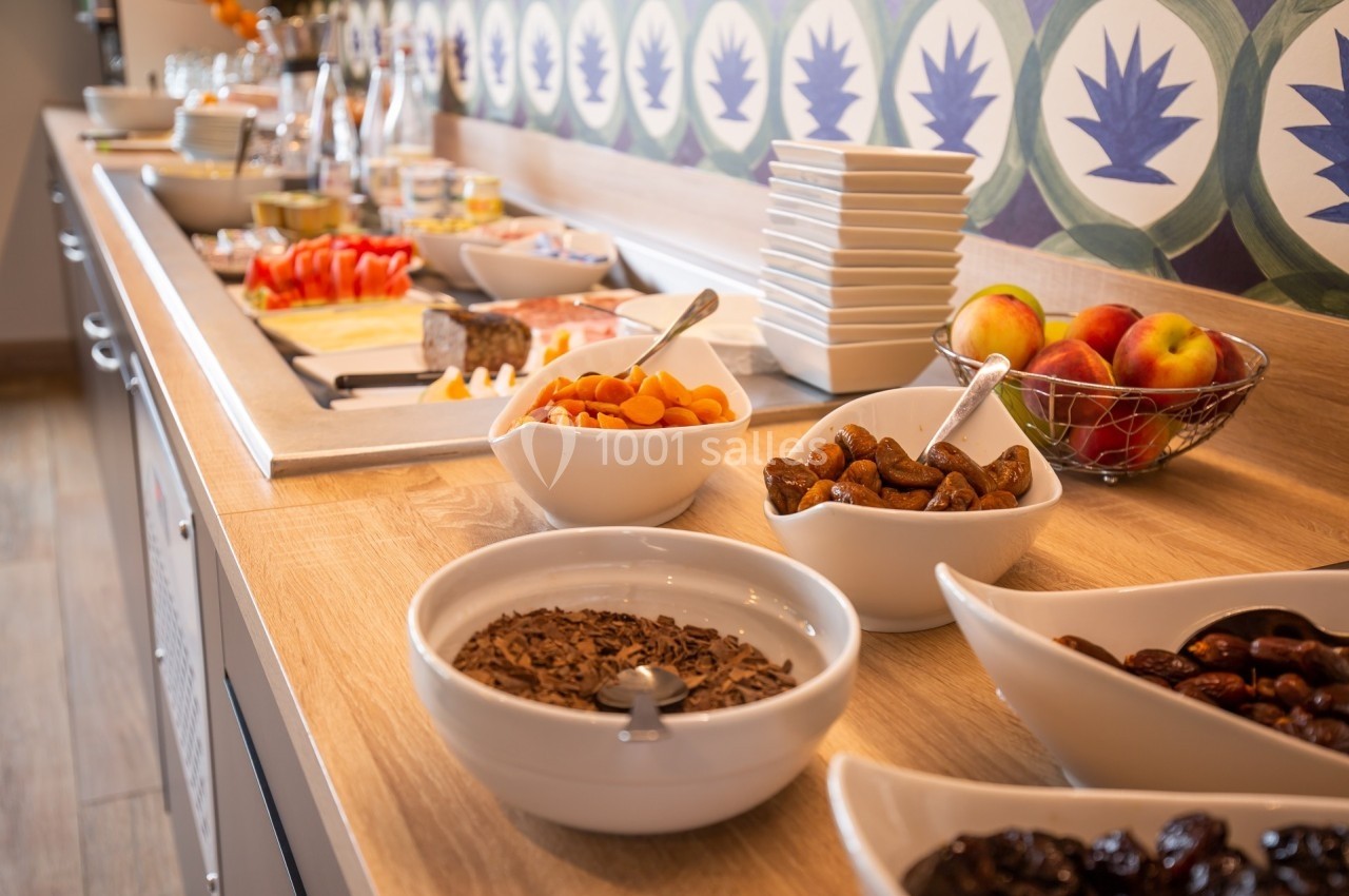 Buffet avec fruits, fruits secs, charcuterie et condiments disposés sur un comptoir en bois.
