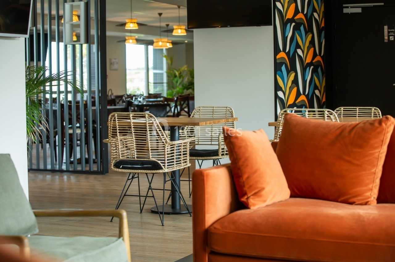 Espace intérieur lumineux avec des fauteuils en rotin, une table en bois et une décoration murale colorée.