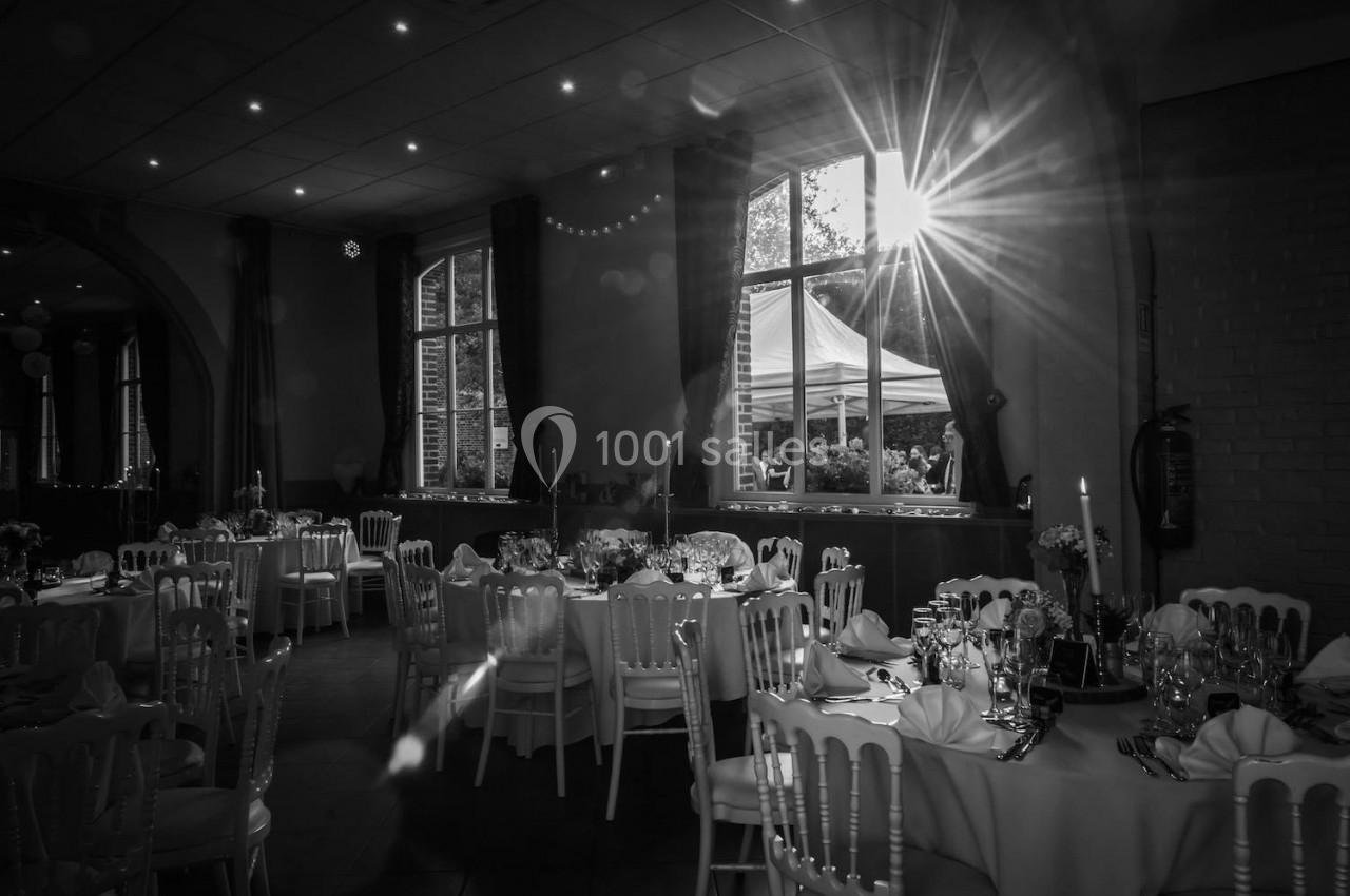 Location salle Comines (Nord) - Les Salons du Château - France Evénement #31 Salle de réception décorée avec des tables dressées, éclairée par la lumière du soleil traversant une grande fenêtre.