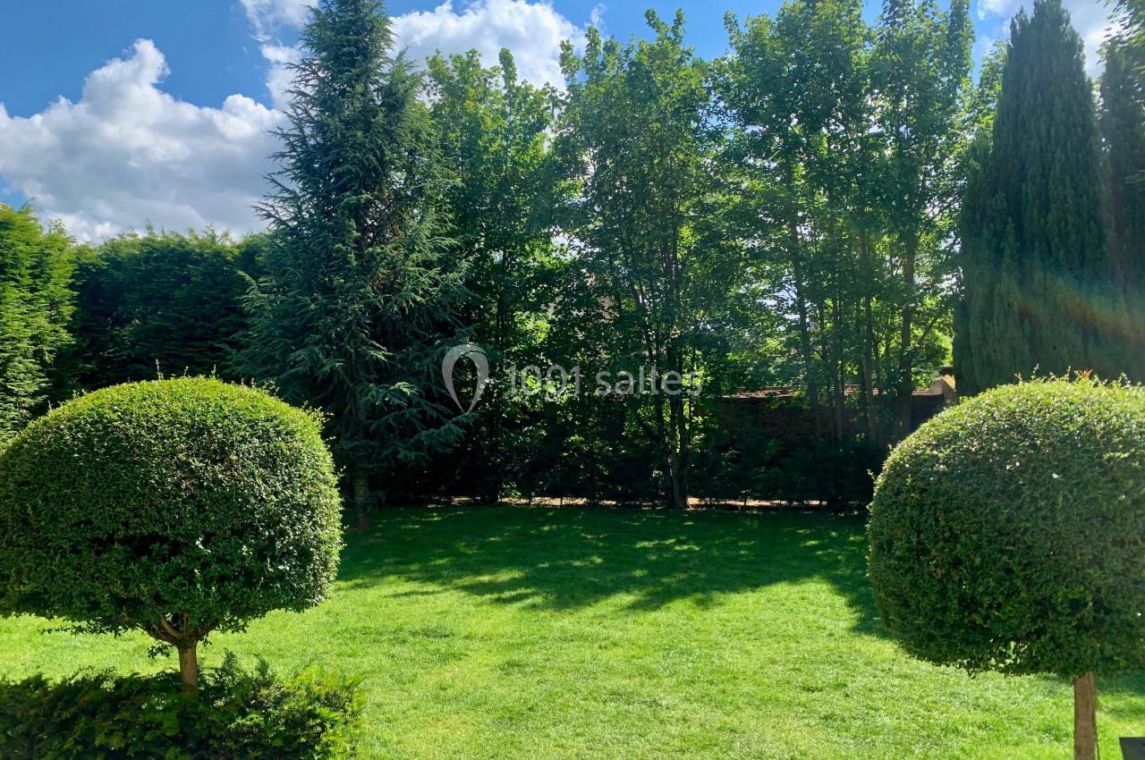 Location salle Comines (Nord) - Les Salons du Château - France Evénement #34 Jardin verdoyant avec pelouse, arbres et arbustes taillés, sous un ciel bleu parsemé de nuages.