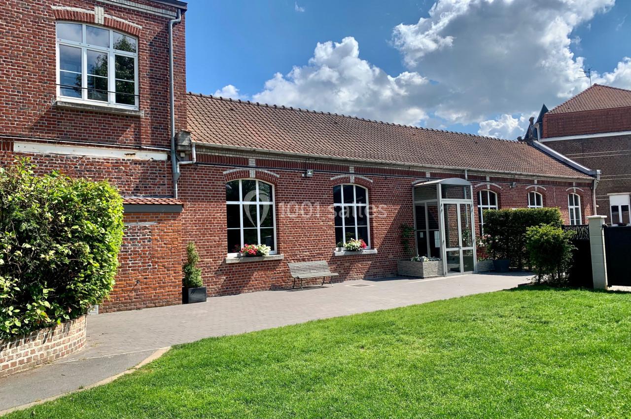 Location salle Comines (Nord) - Les Salons du Château - France Evénement #2 Bâtiment en briques rouges avec fenêtres blanches, entouré de pelouse et de haies sous un ciel partiellement nuageux.