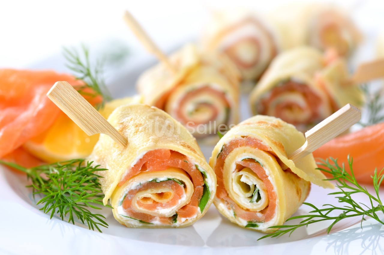 Roulés de crêpes garnis de saumon fumé, fromage frais et herbes, présentés avec des brins d'aneth.