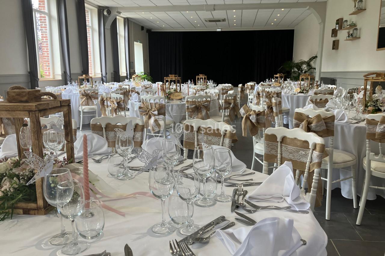 Location salle Comines (Nord) - Les Salons du Château - France Evénement #30 Salle de réception décorée pour un mariage, avec tables dressées, nappes blanches et chaises ornées de rubans beiges.