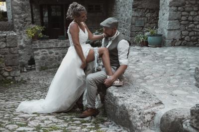 Miniature Mariage Labeaume Femme assise, vêtue d'une robe blanche fluide, posant avec une expression sereine sur fond neutre.