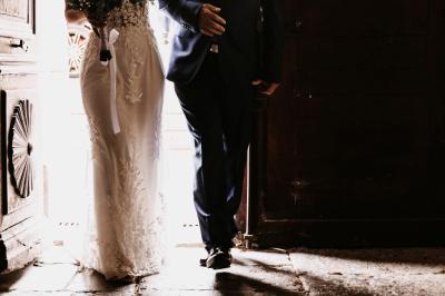 Miniature Mariage Labeaume Femme assise, vêtue d'une robe blanche fluide, posant avec une expression sereine sur fond neutre.