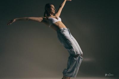 Miniature Shooting Portrait Danse  Femme assise, vêtue d'une robe blanche fluide, posant avec une expression sereine sur fond neutre.