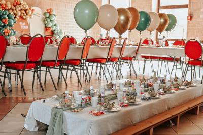 Table décorée avec des bougies torsadées, fleurs séchées et chemin de table rouge dans un cadre chaleureux.