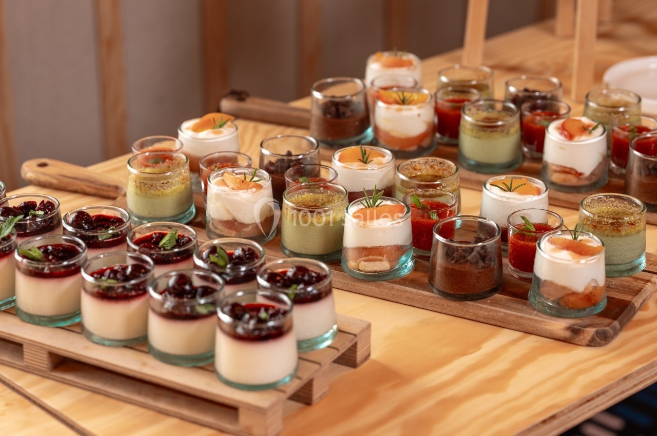 Desserts variés en verrines, disposés sur des plateaux en bois, avec des garnitures colorées et diversifiées.