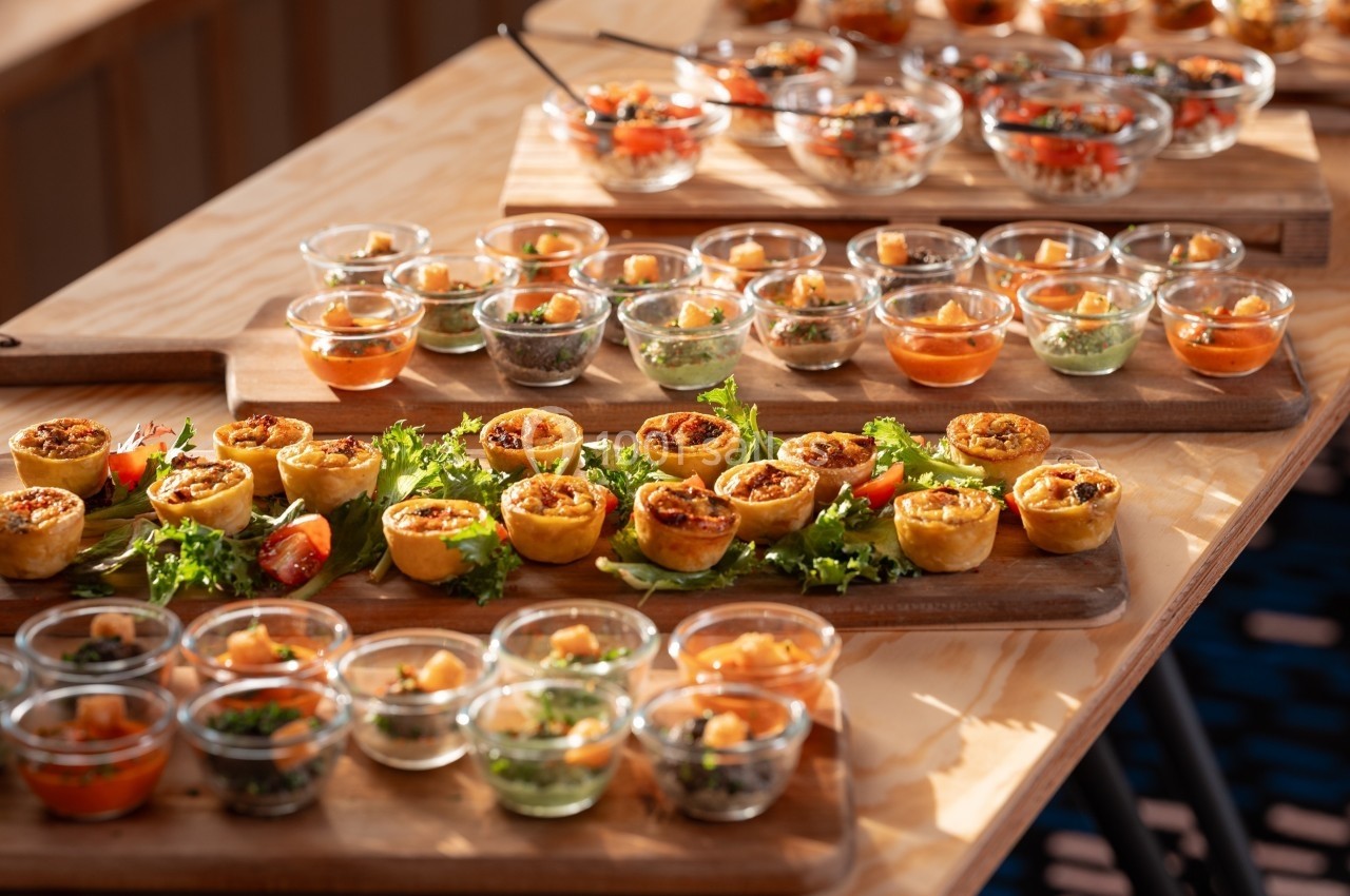 Plateaux en bois garnis de verrines et de bouchées salées disposés sur une table en lumière naturelle.