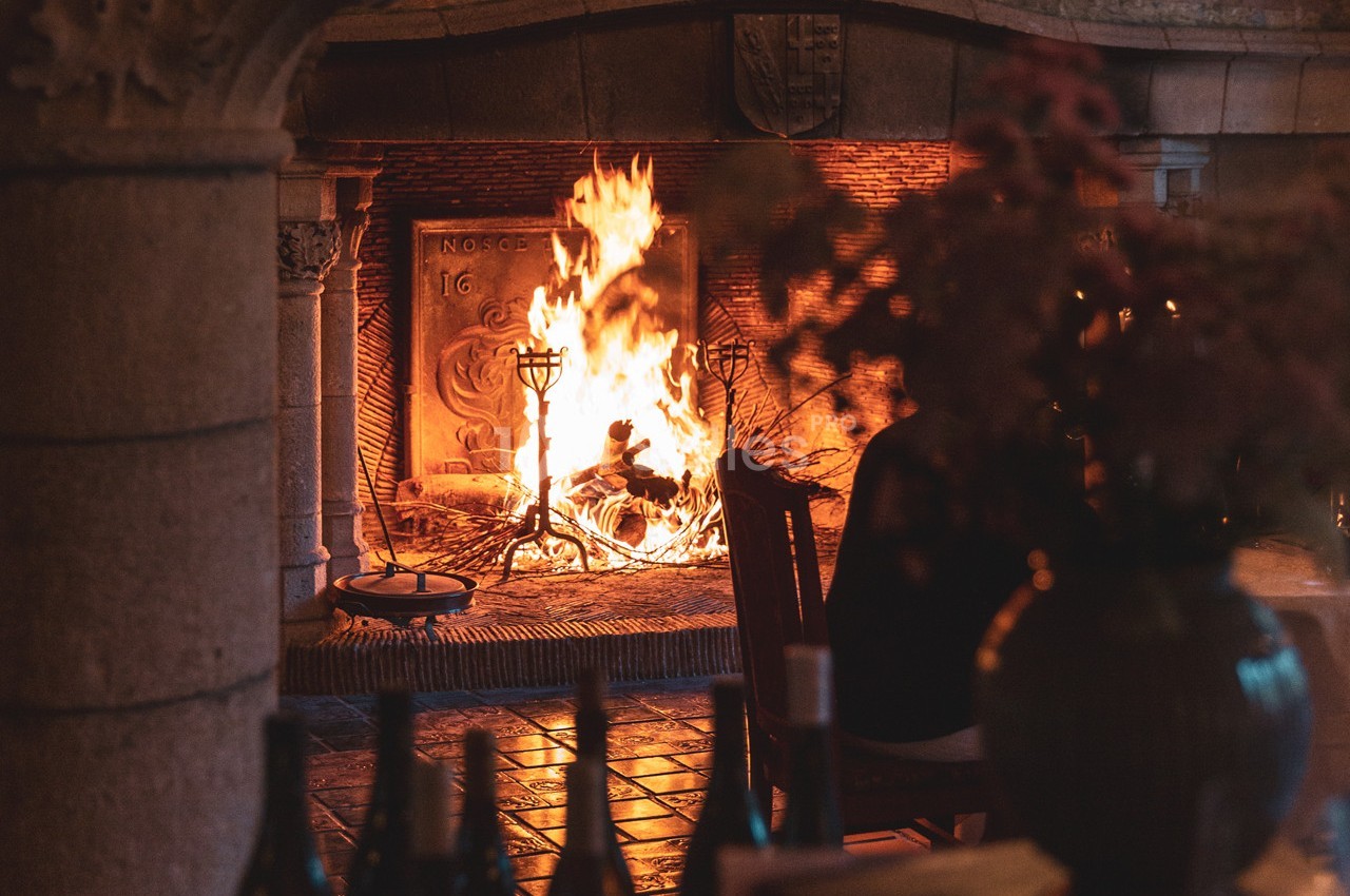 Cheminée en pierre avec un feu de bois allumé, éclairant une pièce chaleureuse avec des objets décoratifs au premier plan.