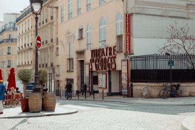 Façade du Théâtre Saint-Georges dans une rue calme avec des passants et des bâtiments environnants.