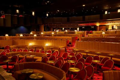 Miniature Auditorium Lido Intérieur d'une pièce aux motifs colorés et symétriques avec des murs en bois, des miroirs et un plafond lumineux.