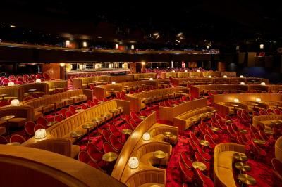 Miniature Auditorium Lido Intérieur d'une pièce aux motifs colorés et symétriques avec des murs en bois, des miroirs et un plafond lumineux.