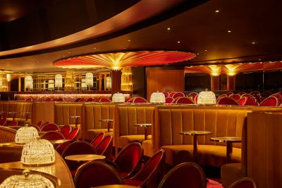 Miniature Auditorium Lido Intérieur d'une pièce aux motifs colorés et symétriques avec des murs en bois, des miroirs et un plafond lumineux.