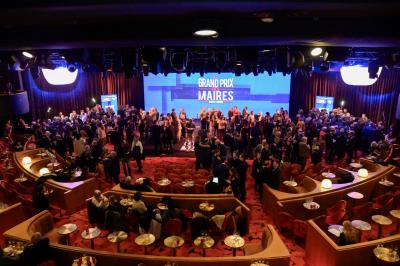 Miniature Événement Grand Prix des Maires Intérieur d'une pièce aux motifs colorés et symétriques avec des murs en bois, des miroirs et un plafond lumineux.