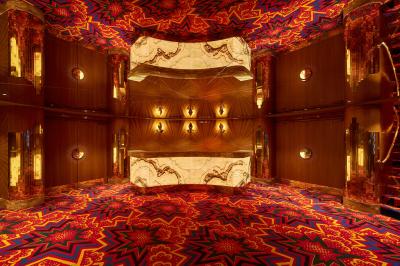 Miniature Hall d'accueil Intérieur d'une pièce aux motifs colorés et symétriques avec des murs en bois, des miroirs et un plafond lumineux.