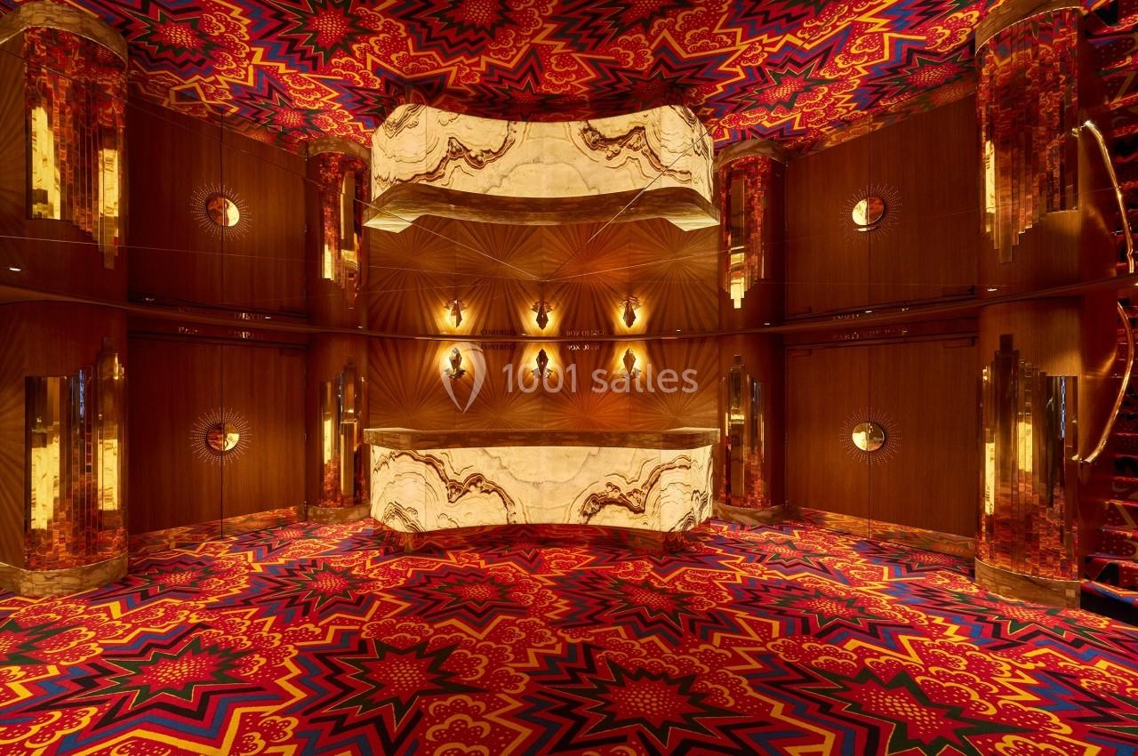 Intérieur d'une pièce aux motifs colorés et symétriques avec des murs en bois, des miroirs et un plafond lumineux.