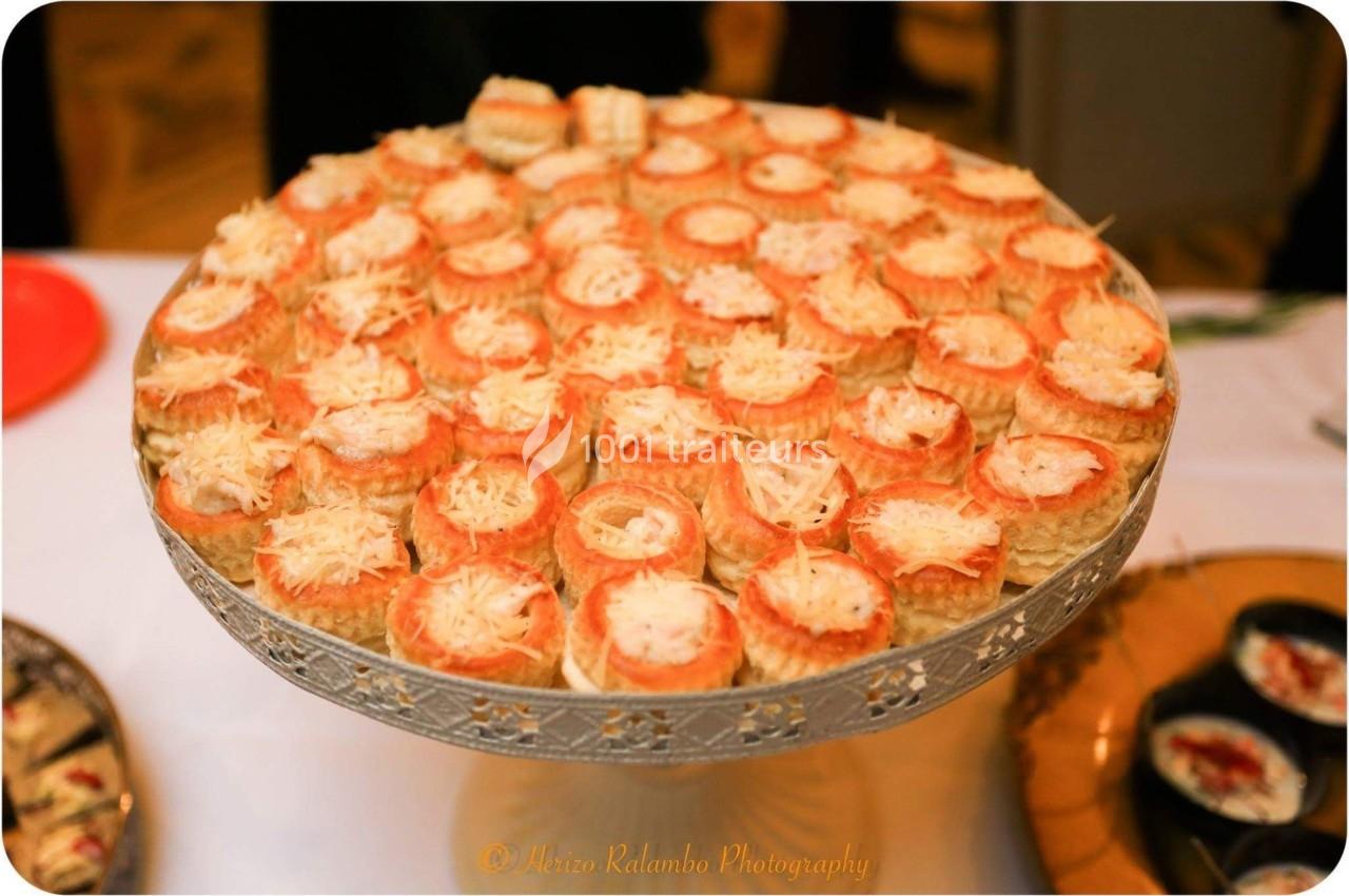 Plateau de bouchées feuilletées garnies de fromage râpé, présenté sur un support décoratif en métal argenté.