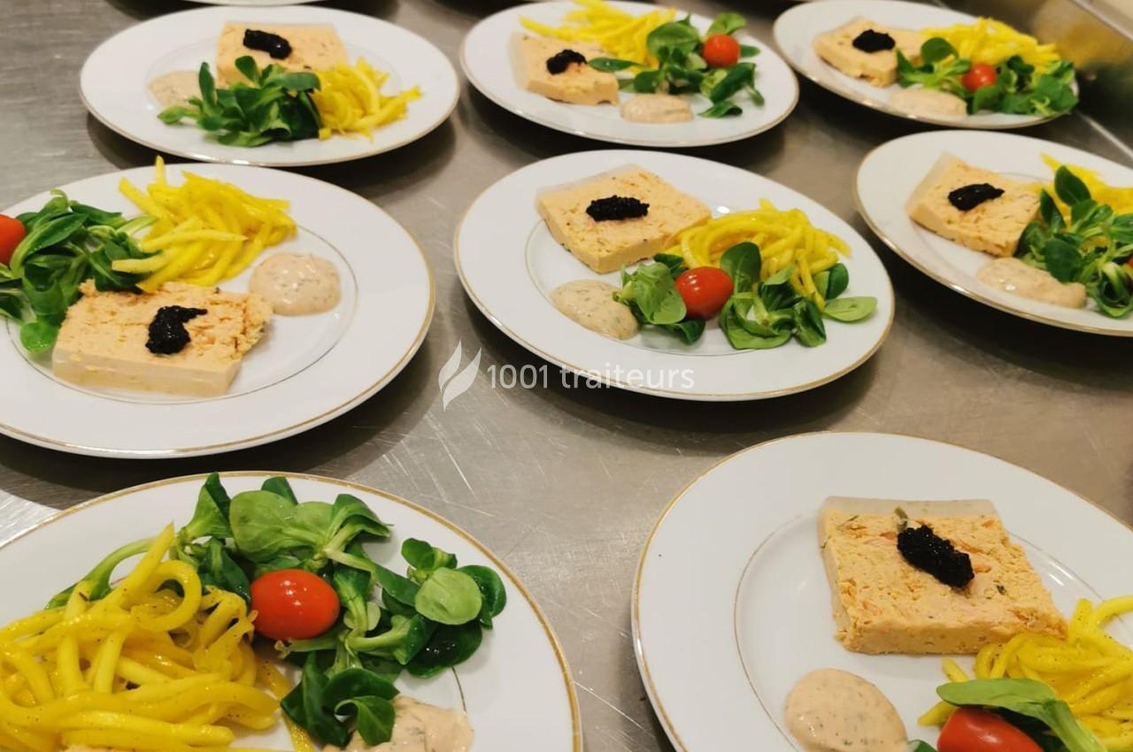 Assiettes dressées avec terrine garnie de caviar, salade verte, tomates cerises, légumes jaunes et sauce en accompagnement.