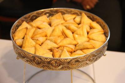 Plateau en métal doré rempli de samoussas dorés et croustillants, posé sur une table blanche.