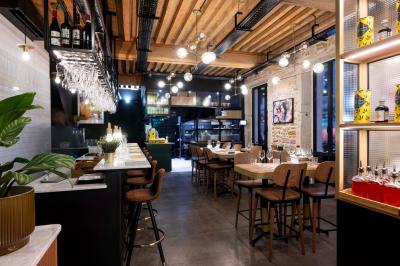 Étagères en bois remplies de produits alimentaires et ménagers dans une petite épicerie lumineuse avec sol carrelé.