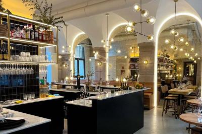 Étagères en bois remplies de produits alimentaires et ménagers dans une petite épicerie lumineuse avec sol carrelé.