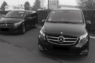 Miniature Regency Limo Coach #3 Alignement de véhicules noirs stationnés devant un bâtiment en pierre avec arcades, sous un ciel dégagé.