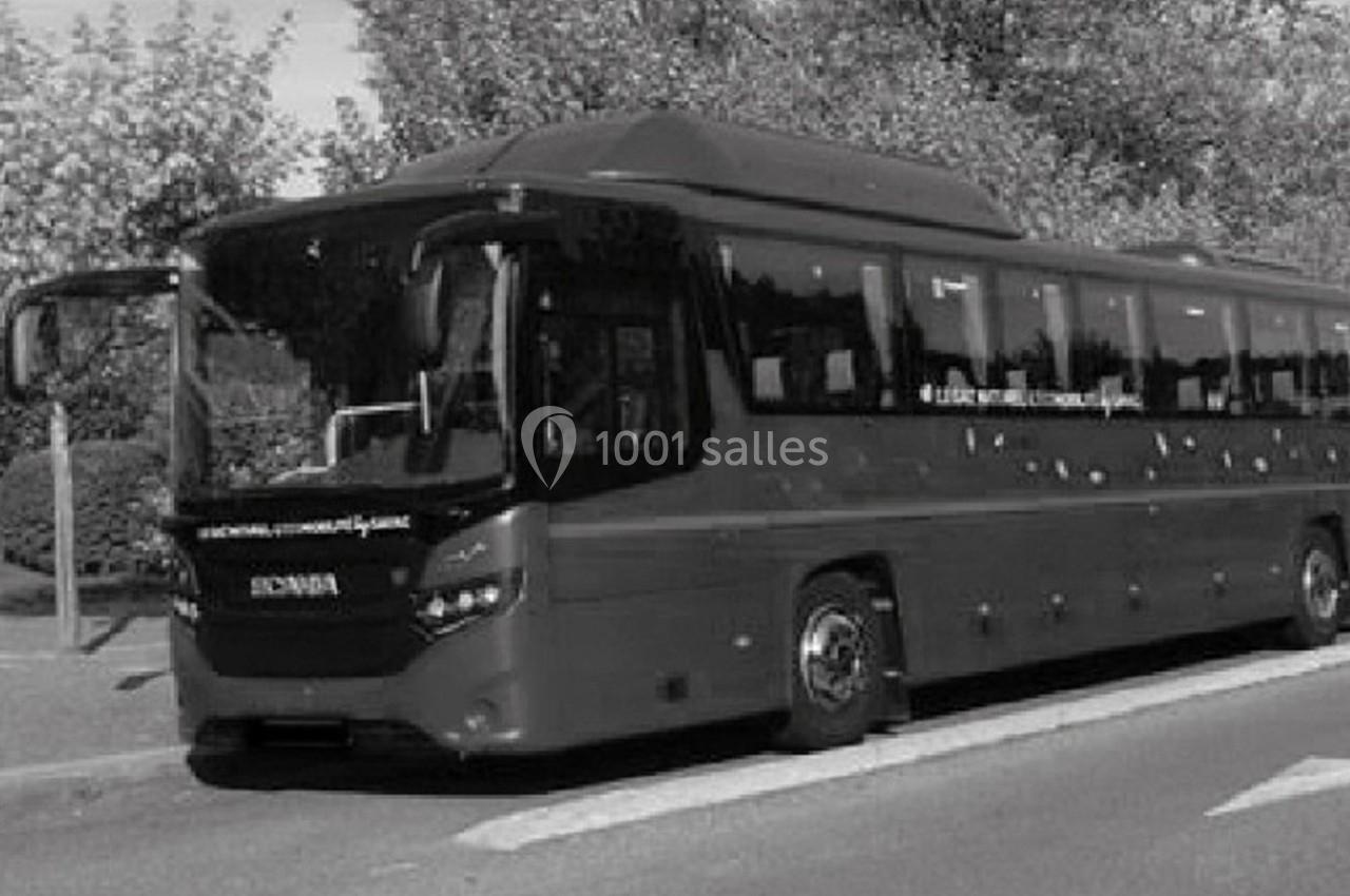 Autocar stationné sur une route bordée d'arbres, avec une porte ouverte à l'avant.