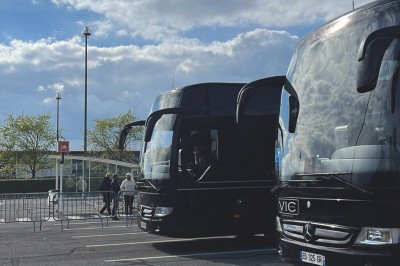 Miniature Regency Limo Coach #11 Alignement de véhicules noirs stationnés devant un bâtiment en pierre avec arcades, sous un ciel dégagé.