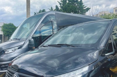 Miniature Regency Limo Coach #20 Alignement de véhicules noirs stationnés devant un bâtiment en pierre avec arcades, sous un ciel dégagé.