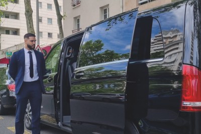 Miniature Regency Limo Coach #21 Alignement de véhicules noirs stationnés devant un bâtiment en pierre avec arcades, sous un ciel dégagé.
