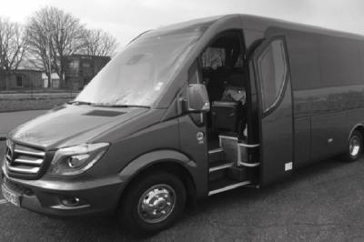 Fourgonnette noire avec portes latérales et arrière ouvertes, montrant un siège accessible et une rampe déployée.